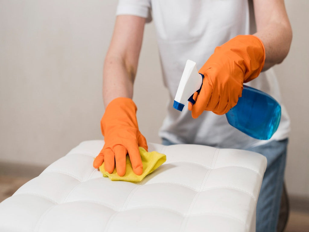 Person cleaning a mattress surface safely using cloth and spray