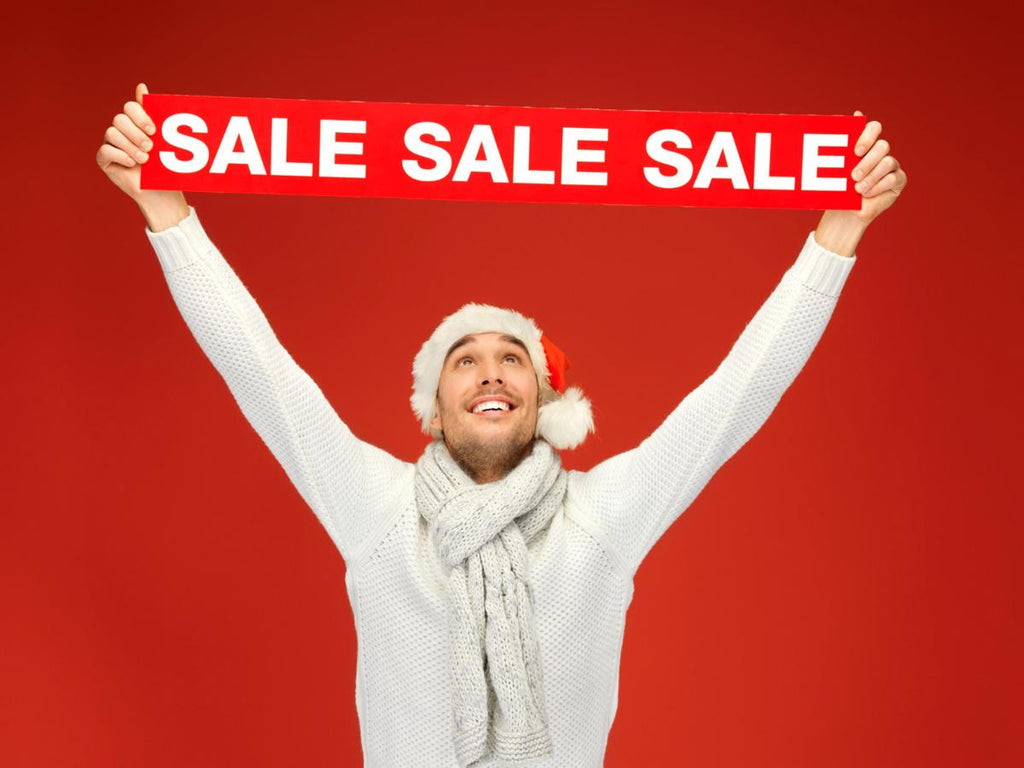 Man celebrating a January sale while holding a red SALE sign on a festive background
