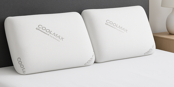 Two white Coolmax pillows on a bed with a gray headboard.