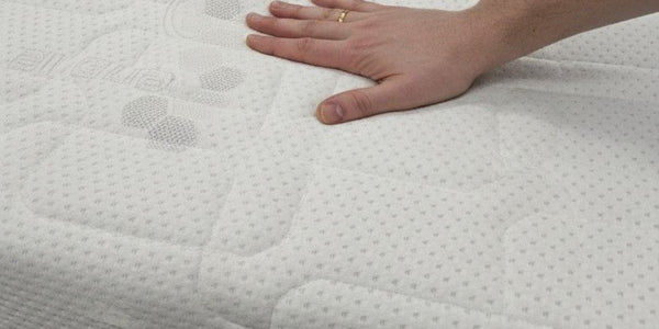 Hand touching a textured mattress surface